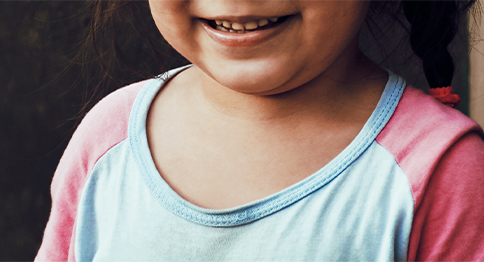 طفلة تتوسط الصورة ، على وجهها ابتسامة جميلة.